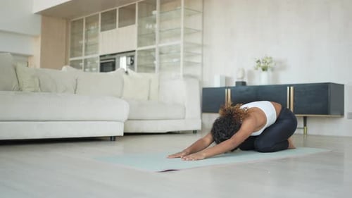 Woman Stretches on Yoga Mat at Home