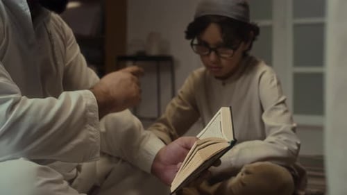 Little Boy Receiving Religious Education from Father Who Reading Koran