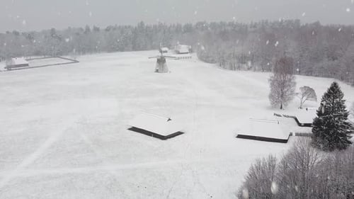 Ländliche Dorfgebäude und Mühle, die bei nebligem Schneefall schneebedeckt sind, Luftbild