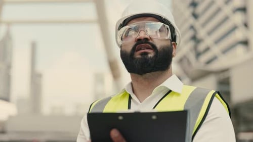 Engineer With Beard Writing on Clipboard in City