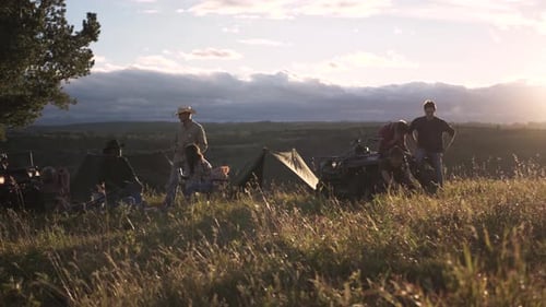 Family camping at sunset in a grassy field