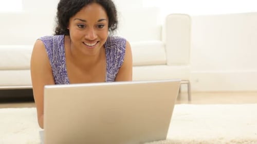 Smiling Woman Lying on Rug Using Laptop