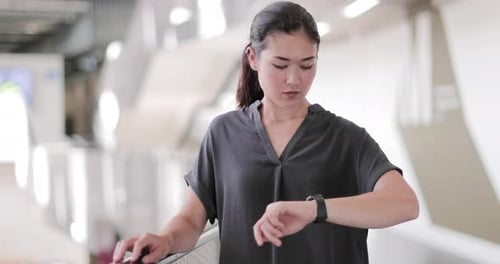 Young Woman Checking Smartwatch in Modern Setting