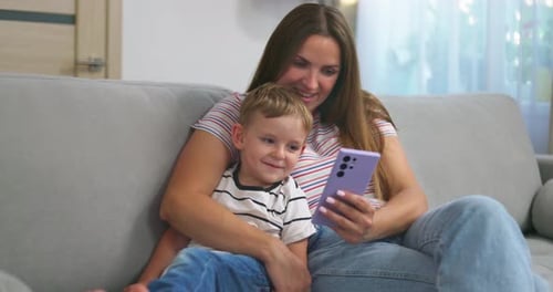 Woman and Child Interact with Phone on Couch