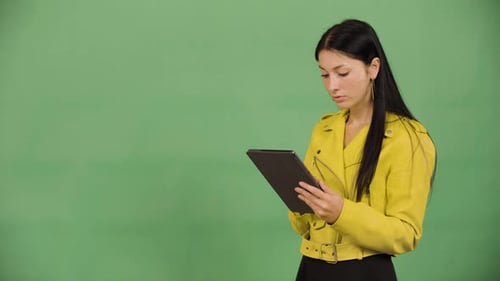 A Young Beautiful Caucasian Woman Works on a Tablet Green Screen Studio