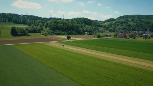 Aerial view of tractor harvester working in green agriculture field in spring