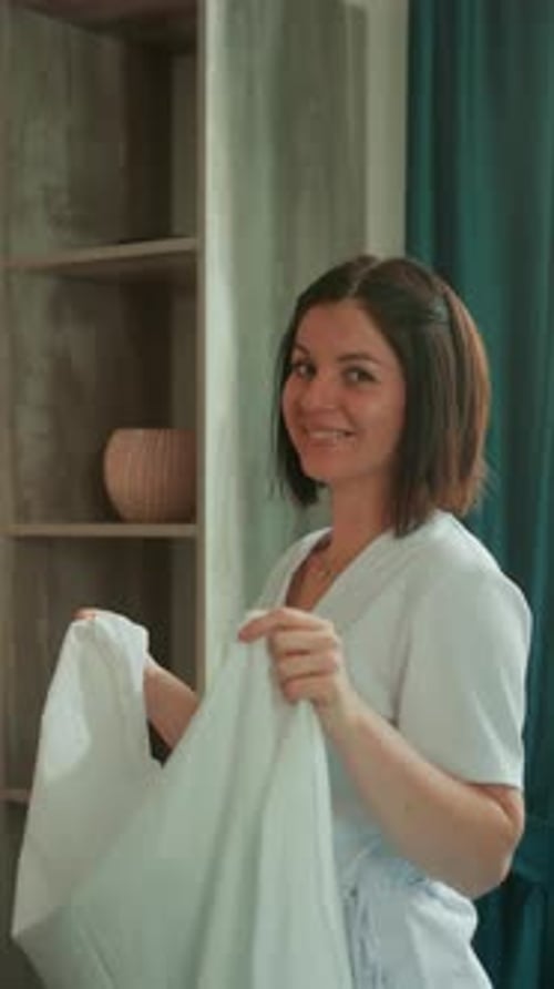 Smiling Woman Holds a White Sheet Indoors