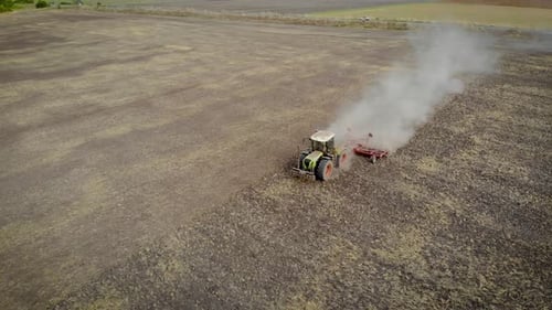 Сopter Flies Over Modern Farm Tractor with Cultivator Loosen Ground Near Highway with Car