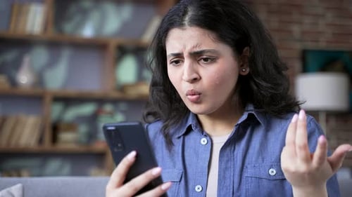 Worried Young Woman Looking at Mobile Phone