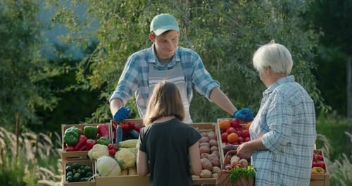 An Elderly Woman and Her Granddaughter Buy Vegetables Together at a Farmers Market