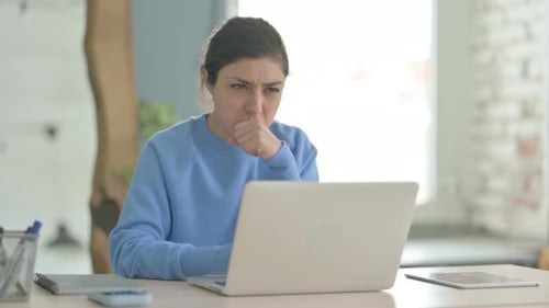 Indische Frau hustet bei der Arbeit am Laptop