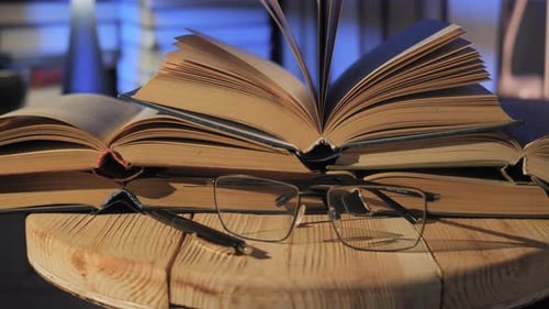 Open Books Stacked on Rustic Desk with Warm Ambient Lighting