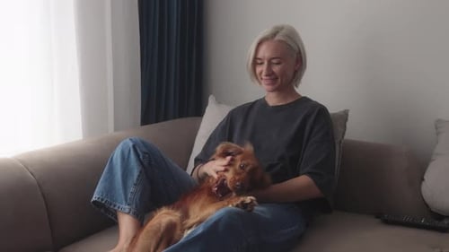Woman Cuddling Dog on Couch at Home