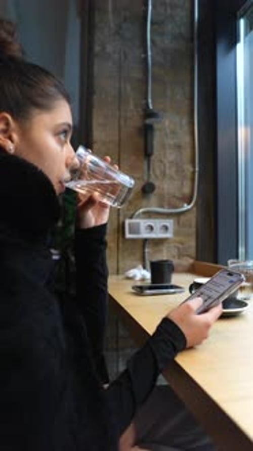 Close Up Portrait of Young Beautiful Girl Drinking Water with Smartphone in Hands