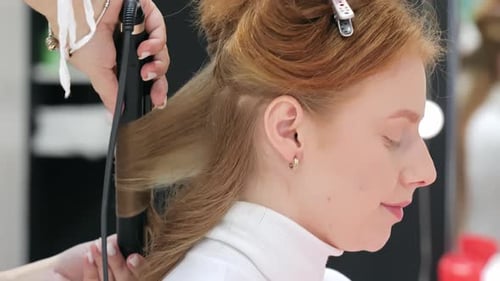 A Hairstylist Uses a Curling Iron to Style a Woman's Hair in a Salon The Detailed Process of Hair