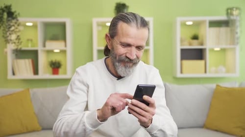 Senior Man Using Smartphone Sitting on Couch