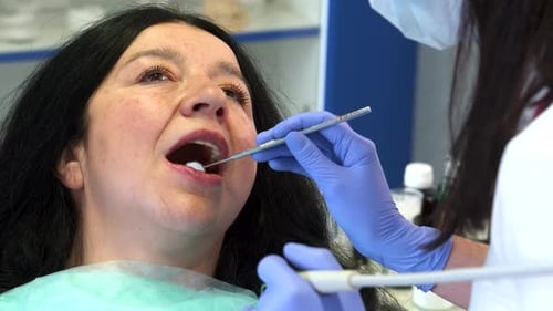 Dental Hygienist Performs Root Planing on a Senior Female Patient