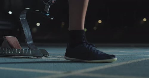 Cinematic macro shot of young man with disability who uses legs prosthesis prepares for launching