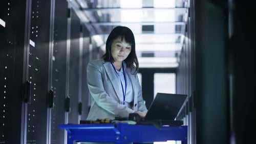 Woman Working on Laptop in Modern Server Room