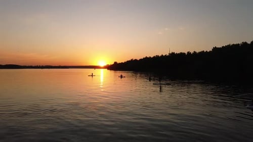 Paddleboarding Silhouettes on Lake at Sunrise