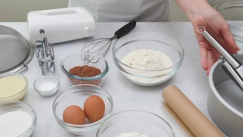 Ingredients and dishes for making chocolate cake close up on kitchen table.