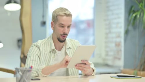 Young Man Celebrating Good News on Tablet