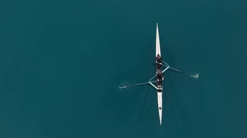 Two Athletes Rowing a Sculling Boat on Calm Blue Water Teamwork and Endurance in Competitive Sport