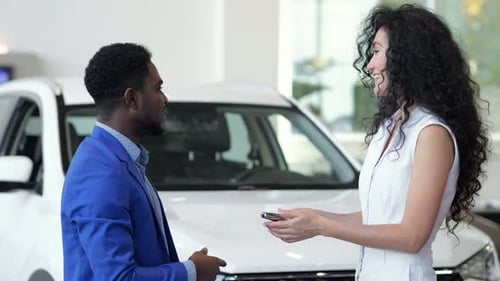 African American Salesman Gives Key to Bought Car to Client