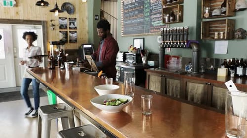 Teamwork at local brewery with bartender and waitress working together