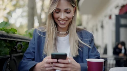 Young Businesswoman Texting on Smartphone at City Cafe