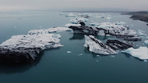 A drone hovers over a glacier lagoon, its surface awash with icebergs of every shape and size in