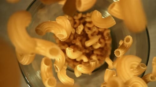 Elbow Macaroni Falling into a Glass Bowl
