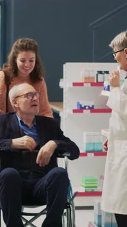 Pharmacist Consults With Senior Man in Wheelchair