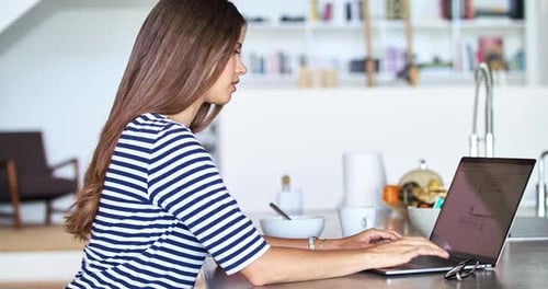 Woman Working on Laptop at Kitchen Table