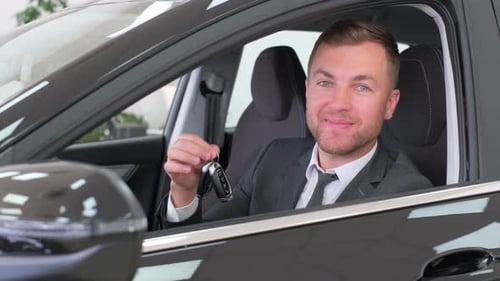 Happy Young Man Sitting in New Car
