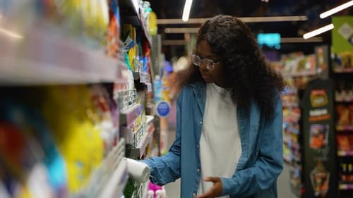 Mujer afroamericana que elige un producto de limpieza para el hogar