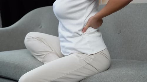 Woman with Back Pain Sitting on Couch