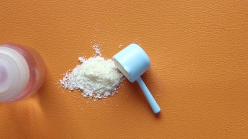 Close Up of Baby Milk Powder and Spoon on Tile Background