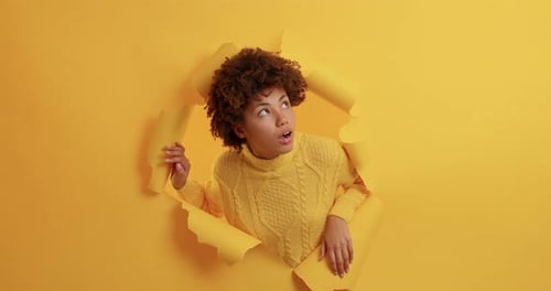 Woman Posing Through a Hole in a Yellow Wall