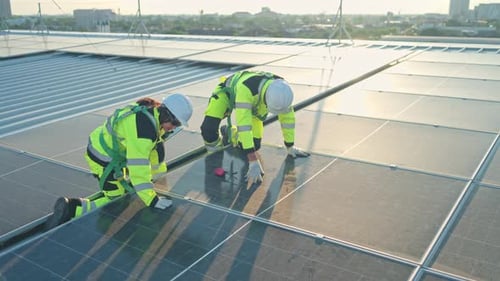 Male and female engineers inspecting rooftop solar panels on a modern building
