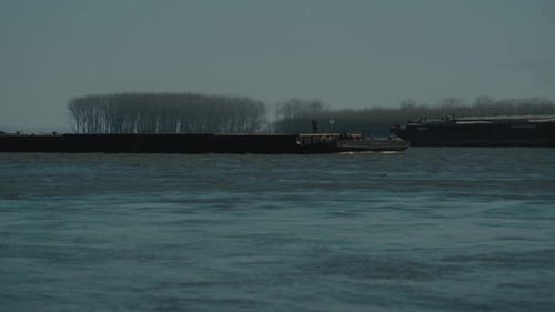 Static close up shot with two large barges navigating on a large river, clear sunny day