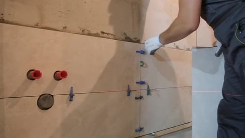 Worker Installing Tiles on Wall