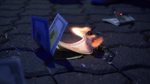 Burning dollar bills on the ground