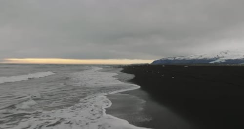 aerial movement over coastline of black beach at diamond beach, Jökulsárlón Glacier Lagoon, iceland