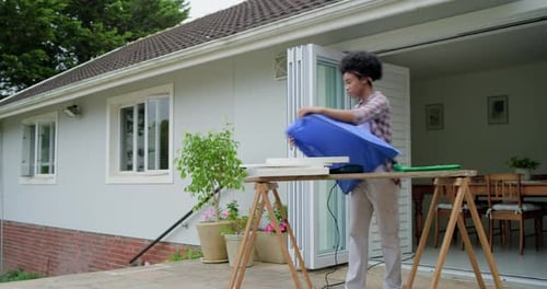 Mulher afro-americana desdobrando tecido azul no banco do pátio, esticando e usando grampeador como moldura