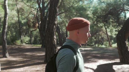 A Young Male Tourist Walks Through a Summer Forest and Takes Pictures