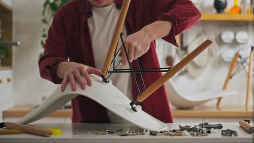 Young Man Assembling Modern Chair at Home