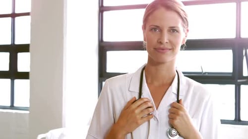 Smiling Doctor Poses with Stethoscope in Hospital