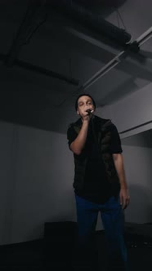 Man Singing into Microphone in Dark Room