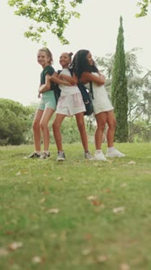 Smiling three girls cross their arms in dance move in the park